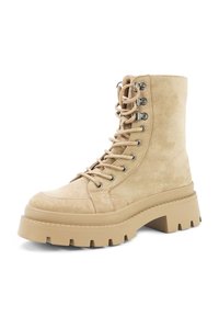 Beige suede ankle boots with a thick rubber sole, round toe, metal eyelets, and laces, featuring a chunky design and textured finish.