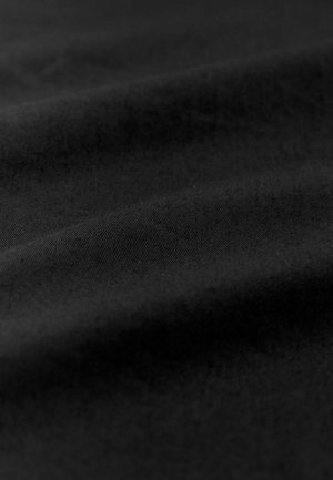 Musta kangas, jossa on sileä tekstuuri, hienovaraiset vinoviivat ja pehmeät laskokset, jotka viittaavat kevyeseen ja joustavaan materiaaliin.