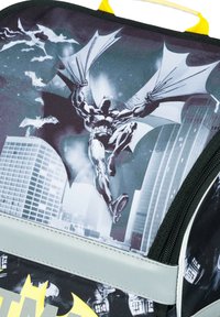 Zaino a tema Batman con design grafico in nero, grigio e giallo, realizzato in tessuto resistente, con cerniera e un manico giallo per il trasporto.
