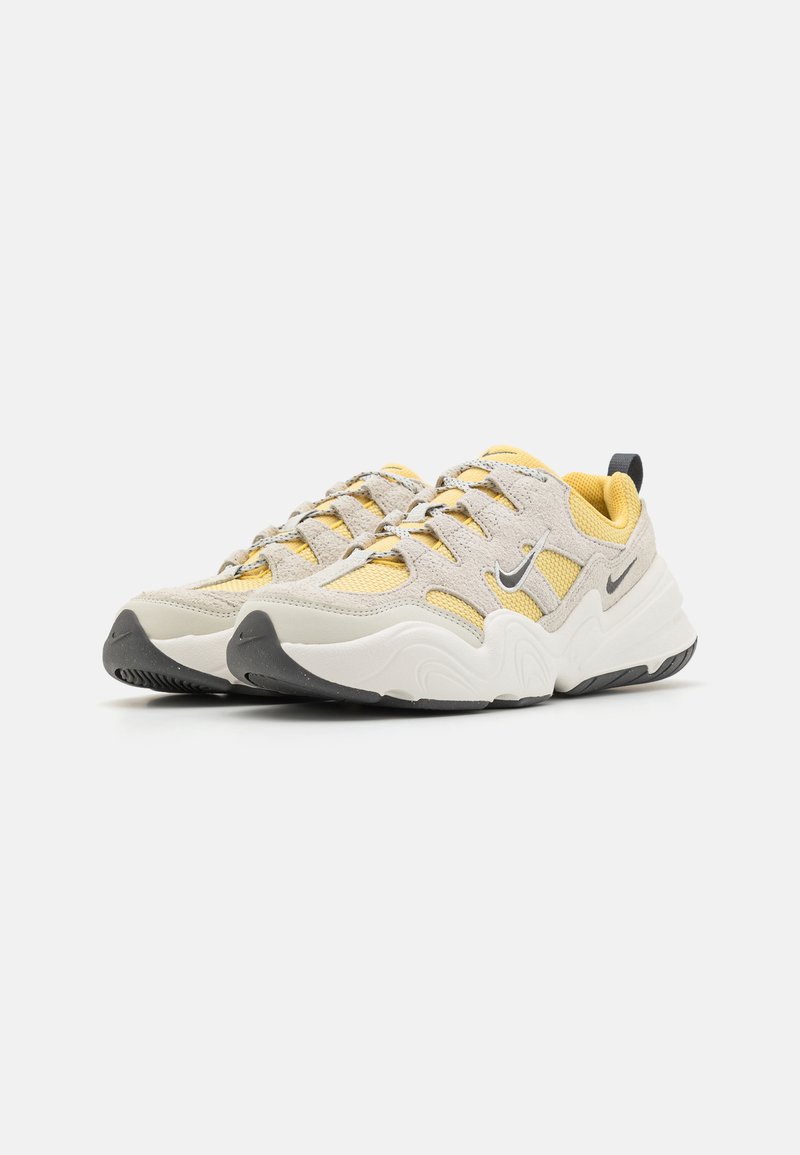 Baskets de sport beiges et jaunes en matériaux en maille et en daim. Dotées d'une semelle rembourrée, d'accents noirs et d'un logo réfléchissant.