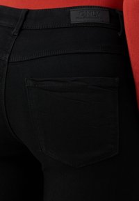 Μαύρα τζιν παντελόνια με πίσω τσέπη, ραφή λεπτομέρεια και ετικέτα με την ένδειξη "ONLY" στη μέση. Το ύφασμα έχει λεία υφή.