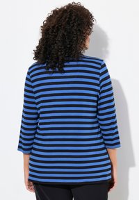 Blå och svart randig topp med trekvartslånga ärmar, mjukt tyg, rund halsringning och en avslappnad passform, med horisontella ränder.