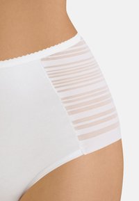 Hochgeschnittene weiße Panties mit solidem Vorderteil und einem transparenten, gestreiften Netzseitenpaneel mit gewellten Kanten.