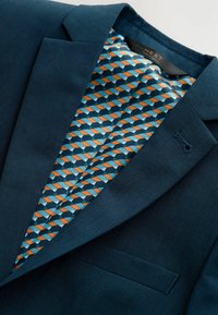 Donkerblauwe blazer van textuurstof. Het binnenvoegsel heeft een geometrisch patroon in blauw, oranje en wit. Enkele borstzak.