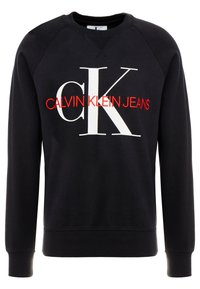 Felpa nera con grandi lettere bianche "cK" e testo rosso "Calvin Klein Jeans" ricamato sul petto, polsini e orlo a coste.