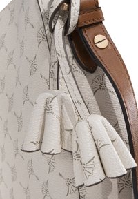 Kožená taška s texturovaným světle šedým povrchem a abstraktním vzorem. Design doplňují hnědé kožené detaily a střapec.