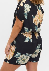 Schwarzer floral bedruckter Playsuit mit kurzen Ärmeln, lockerer Passform, großen Pfirsich- und Cremeblüten sowie grünen Blättern und einem elastischen Bund.