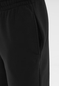 Zwarte joggers van een zachte katoenmix, met een elastische tailleband, zijzakken en subtiele merkbranding nabij de broeknaad.