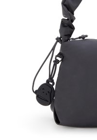 Sort skuldertaske med en glat, mat overflade, en knyttet rem og et gummimonkey charme som dekorativ detalje.