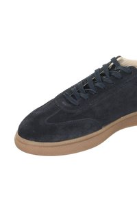 Navy-Suede-Sneaker mit strukturierter Gummisohle, ausgestattet mit Schnürverschluss und genähten Details entlang des Obermaterials. Minimalistisches Design und glatte Oberfläche.