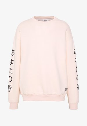 Lichtroze sweatshirt met lange mouwen, geribbelde boorden en zoom, met zwarte tekst langs de mouwen en een logo vlak bij de onderkant.