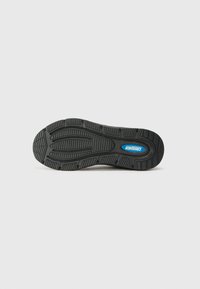 Black rubber shoe sole features a textured tread pattern for grip, with a blue logo at the center. The overall shape is curved and contoured.