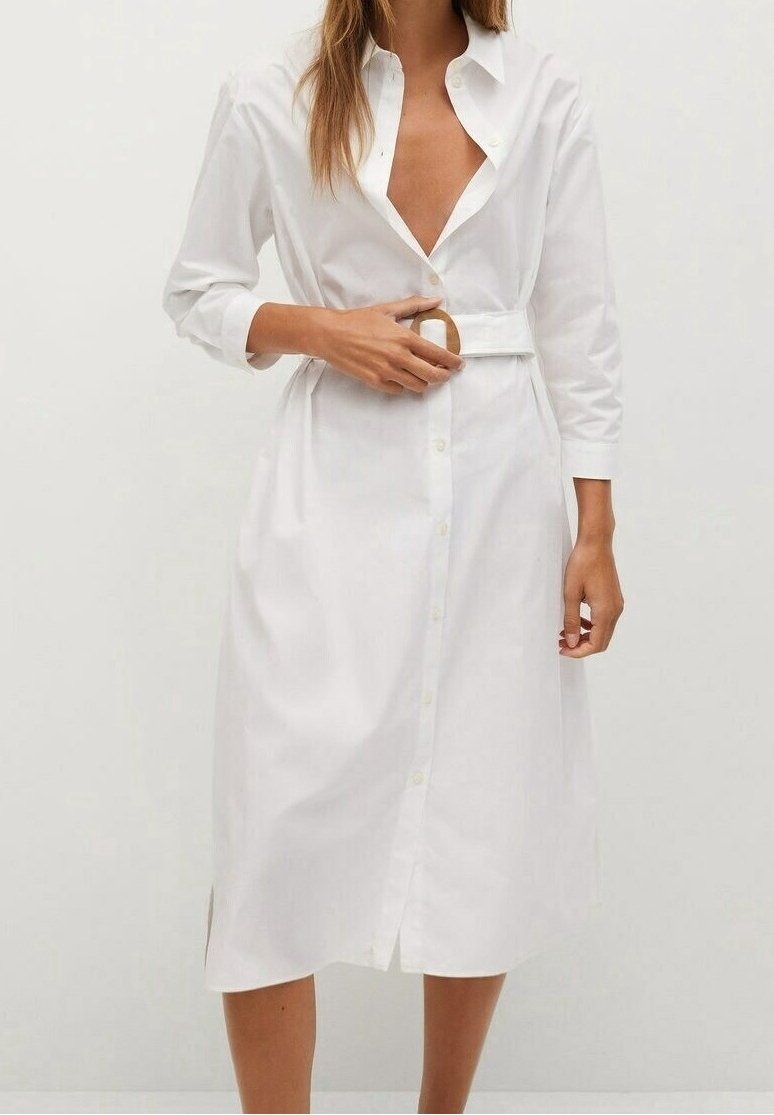 Weißes Hemdkleid mit langen Ärmeln, lockerer Passform, seitlichen Schlitzen und einem Stoffgürtel mit runder Holzschnalle. Glatte Baumwollstruktur.