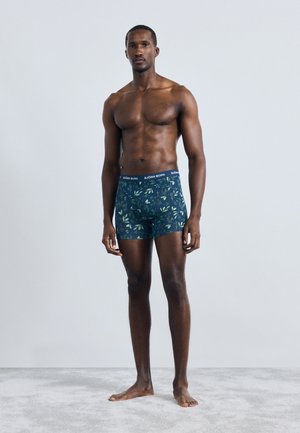 Boxer μ�αγιό σε σκούρο μπλε χρώμα με μοτίβο φύλλων, διαθέτοντας μαύρη ελαστική μέση με το λογότυπο "BJÖRN BORG". Το υλικό φαίνεται μαλακό και ελαστικό.