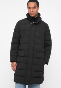 Manteau doudoune noir avec un col haut, texture matelassée et deux poches avant, conçu pour la chaleur et le confort.