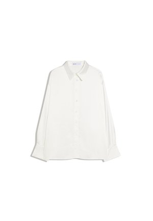 Cămașă albă cu mâneci lungi, cu nasturi, guler ascuțit și manșete late, așezată pe o suprafață plană, pe un fundal alb.