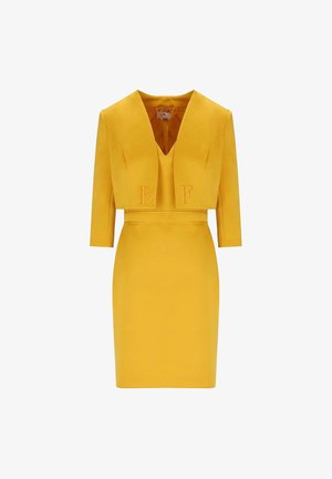 Abito giallo su misura in due pezzi con maniche tre quarti, scollo a V profondo e lettere in rilievo "E" e "F" sulla giacca corta.