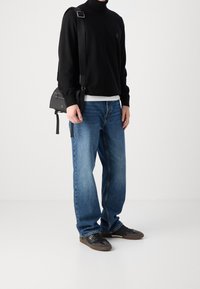 Pull à col roulé noir, jean bleu droit, sac à bandoulière noir et baskets foncées. Design simple avec une coupe décontractée et un style casual.