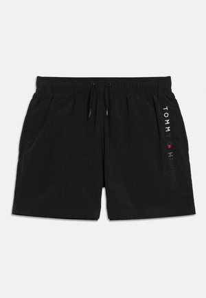 Svart elastiske svømmebukser med snor i midjen, sidelommer og vertikal "Tommy Hilfiger"-logo på høyre ben.