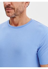 Jasnoniebieska, krótkozasięgowa koszulka z miękkiego materiału bawełnianego, z okrągłym dekoltem i gładką, równą teksturą, bez widocznych wzorów.