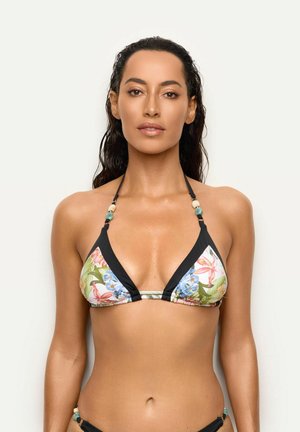 Mujer con cabello largo, oscuro y mojado, que lleva un top de bikini floral con ribete negro sobre un fondo liso y claro.