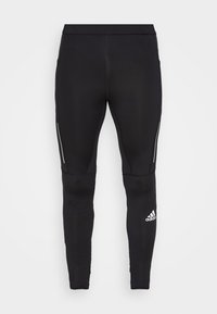 Czarne legginsy sportowe o gładkiej fakturze, z odblaskowymi akcentami po bokach i białym logo na dolnej części nogawki.