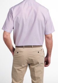 Short-sleeve striped shirt in light purple and white, paired with beige pants. Features a classic collar and back yoke detail.