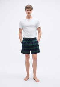 Ανδρικές καρό βερμούδες σε σκούρο πράσινο και μπλε ναυτικό, με άνετη ελαστική μέση και κορδόνι. Κανονική εφαρμογή, ελαφρύ ύφασμα.