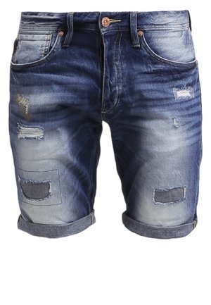T-shirt bleu marine avec motif et poche, associé à un short en jean déchiré. Accessoires : une montre noire et des baskets bordeaux.