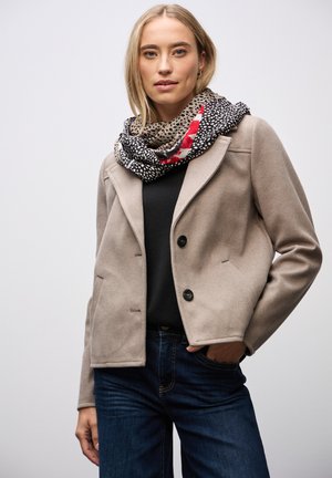 Chaqueta de mezcla de lana beige con solapas de muesca, cierre de dos botones y bolsillos laterales, combinada con una bufanda a rayas en negro y rojo.