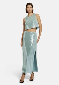 Twee-delig outfit bestaat uit een cropped top en een lange rok van glanzende aqua pailletten, met een zijsplit en een aansluitend ontwerp.
