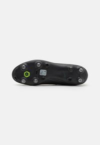 Semelle de crampons de football noire avec six crampons, texturée pour une traction optimale. Présente un accent vert et le logo Nike près du talon.
