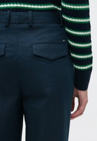 Παντελόνια ναυτικού μπλε με ραμμένη εφαρμογή, ομαλή υφή και δύο πίσω τσέπες. Διαθέτουν θηλιά για ζώνη και ένα μικρό λογότυπο στην τσέπη.