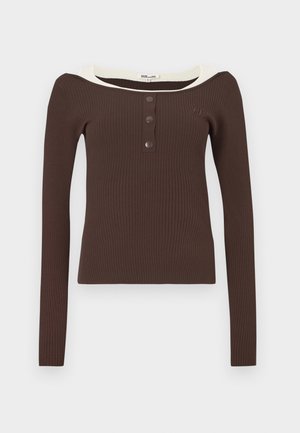 Brązowa prążkowana bluzka z długim rękawem, szerokim kremowym dekoltem i trzema czarnymi guzikami z przodu. Charakteryzuje się dopasowanym krojem i miękką fakturą.