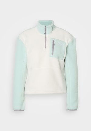 Fleece trui met een wit lijf, lichtblauwe mouwen, halve rits aan de voorkant en een ritssluiting op de borstzak aan de linkerkant.