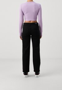 Lila kortärmad topp med ribbad textur, parat med högmidjade svarta jeans som har rak passform och minimal detaljer.