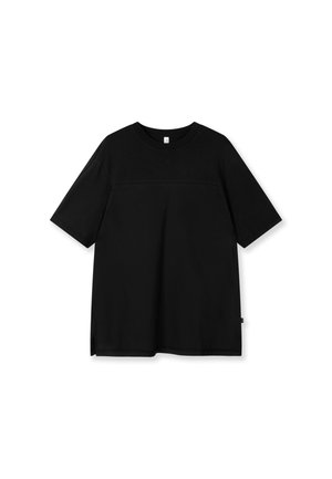 T-shirt noir à manches courtes avec encolure ronde, présentant une couture horizontale subtile sur la poitrine et une petite étiquette en tissu sur le côté.