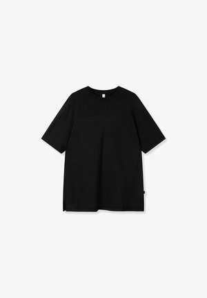 T-shirt noir à manches courtes avec encolure ronde, présentant une couture horizontale subtile sur la poitrine et une petite étiquette en tissu sur le côté.
