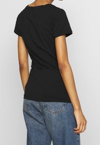 Černé tričko s krátkým rukávem a kulatým výstřihem, slim fit, vyrobené z měkké bavlny. Má čistý, jednoduchý design bez vzorů.