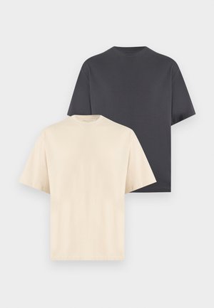 Deux t-shirts unis à col rond, un beige à l'avant et un noir derrière, présentés sur un fond gris clair.