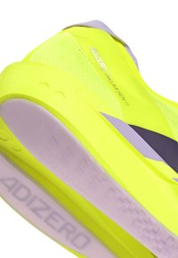 Scarpa da corsa gialla brillante con suola viola e testo "Adizero Takumi Sen 11" sulla parte superiore, che mostra i dettagli del tallone e della intersuola.