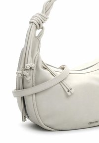 Sac à main en cuir blanc avec une forme incurvée, une surface texturée, une poignée nouée et une fermeture éclair. Présente des coutures discrètes et des accents métalliques.