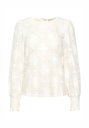 Haut en dentelle blanche avec un motif floral, encolure ronde, manches longues bouffantes et poignets froncés. Fermeture à boutons au dos.