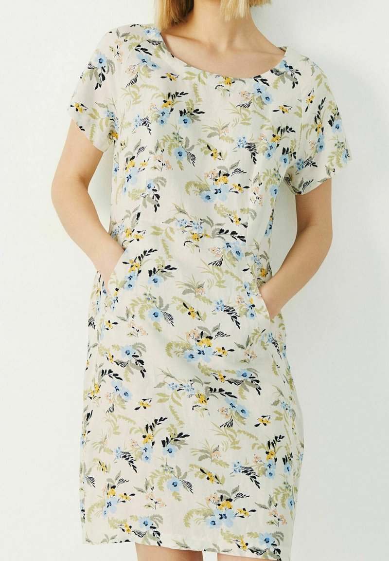 Vestido floral con una tela de color beige claro adornada con flores azules, verdes y amarillas. Incluye mangas cortas y bolsillos laterales.