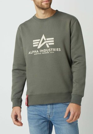 Olijfgroene sweatshirt met een ronde hals, voorzien van een wit logo en tekst. Ribgebreide manchetten en zoom, met een rode label aan de zijkant.