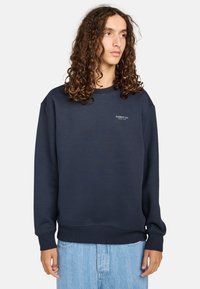 Felpa girocollo blu navy realizzata in morbido tessuto, con un piccolo logo grigio sul petto e polsini e orlo a coste.