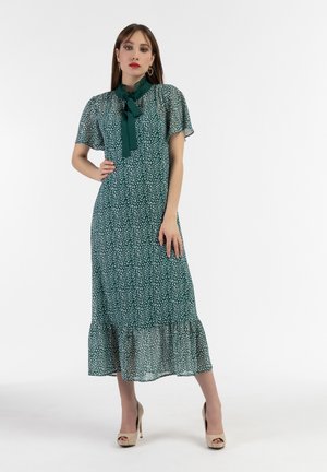 Rochie midi verde cu un imprimeu floral alb delicat, decolteu volanat, mâneci scurte transparente și tiv evazat. Purtați cu tocuri bej.