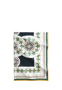 Écharpe en soie présentant un design géométrique avec des motifs circulaires, dans des couleurs noir, blanc et vert, avec des bordures accentuées en jaune et teal.