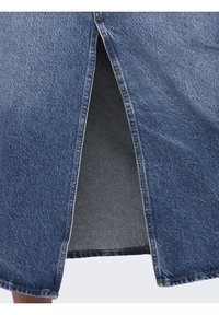 Jeanskjol med en slits fram, i medelblå färg och klassisk vävstruktur. Nederkant med råa kanter och synliga sömnadsdetaljer.