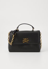 Borsa a tracolla in pelle nera con una catena dorata e manico. Presenta un dettaglio con il logo sul fronte e un design strutturato con chiusura a pattina.